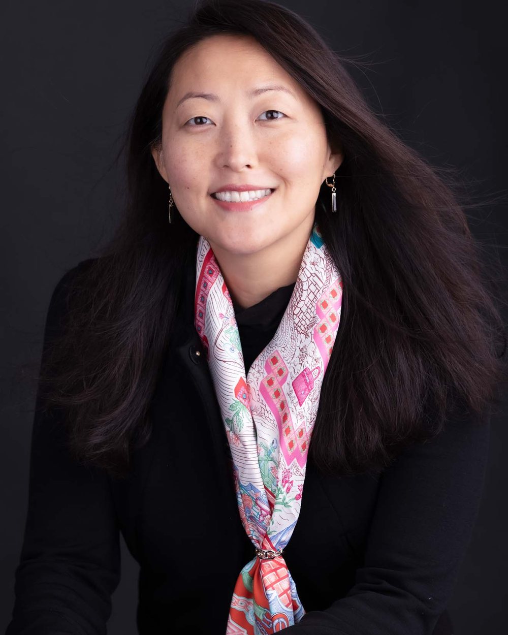Michelle Sohn, smiling, in a black jacket and a patterned silk scarf