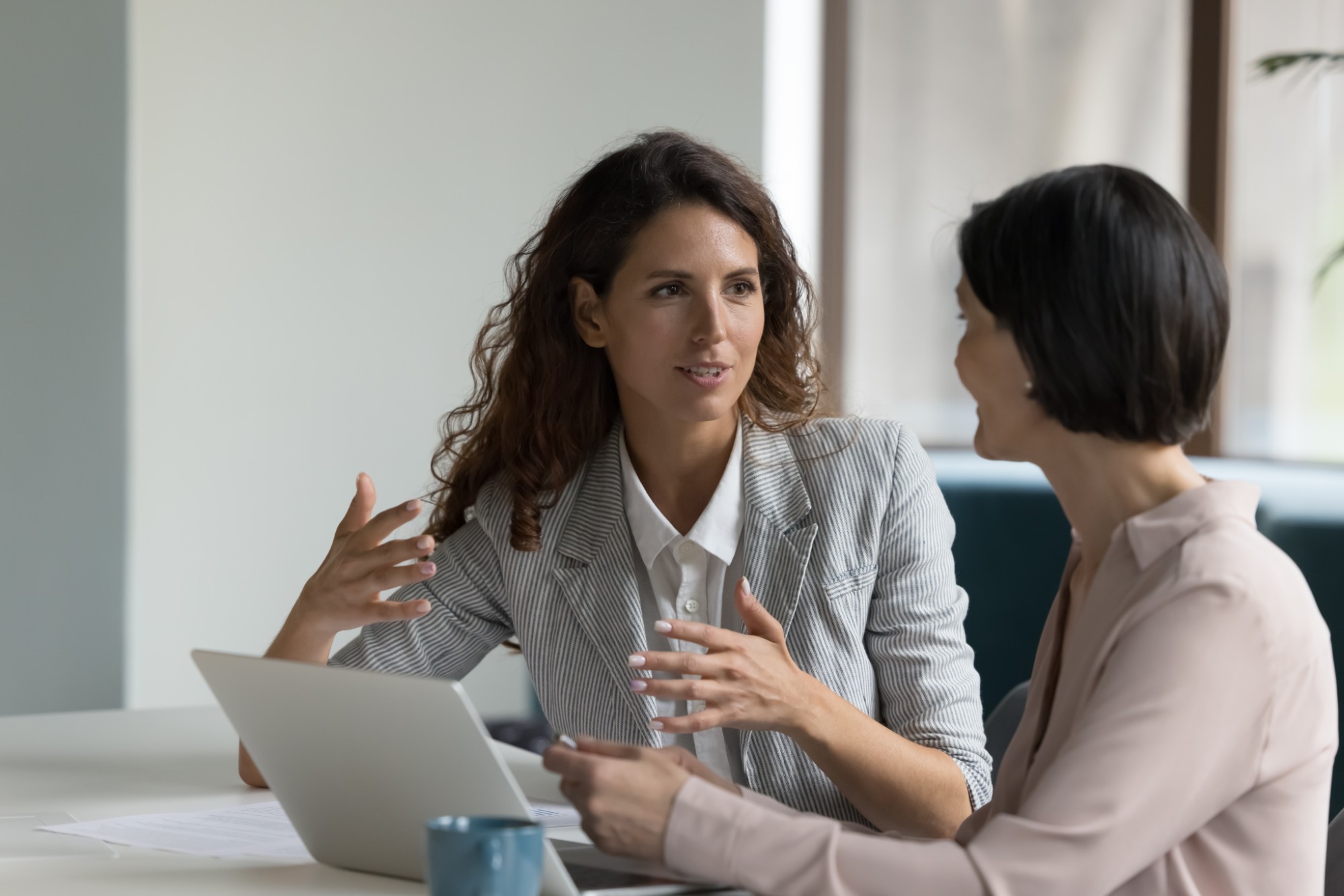 Two professional women in a focused one-to-one conversation at a desk